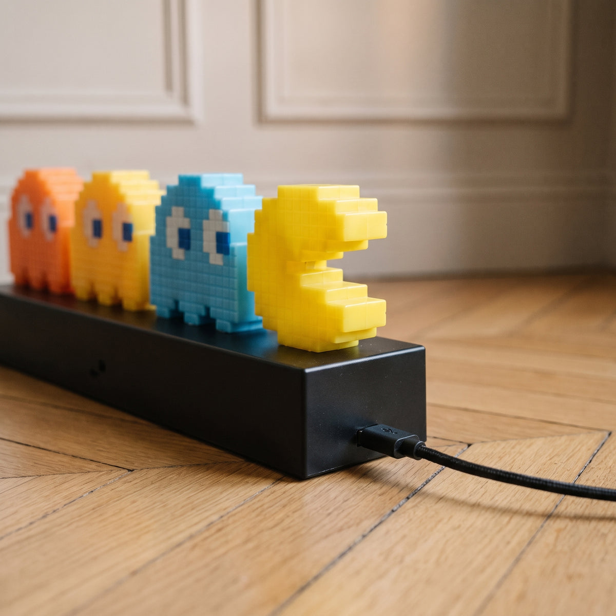 Gros plan sur le socle noir de la lampe Pac Man et son câble USB branché Image