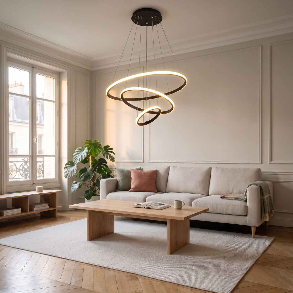 Plafonnier LED suspendu noir à trois anneaux dans un salon lumineux aux murs beiges