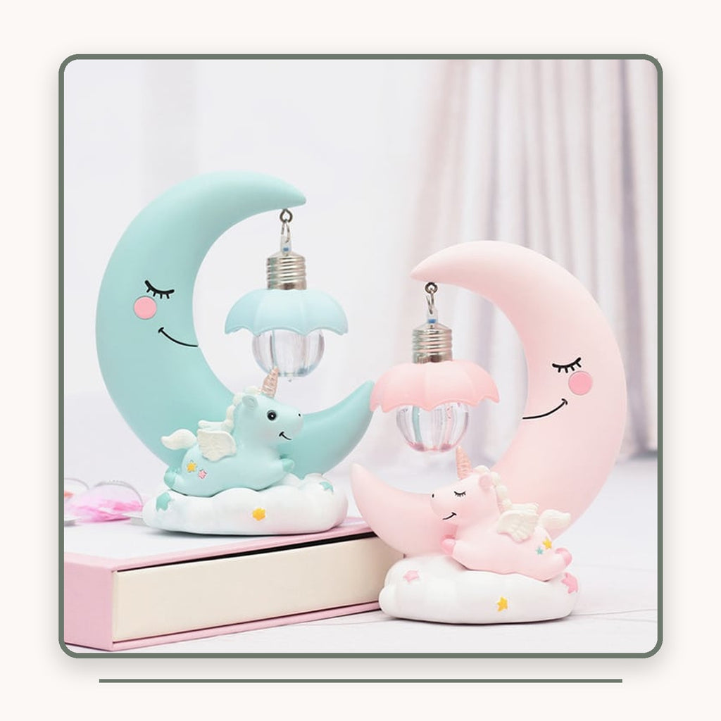Veilleuses lune licorne verte et rose posées près de livres