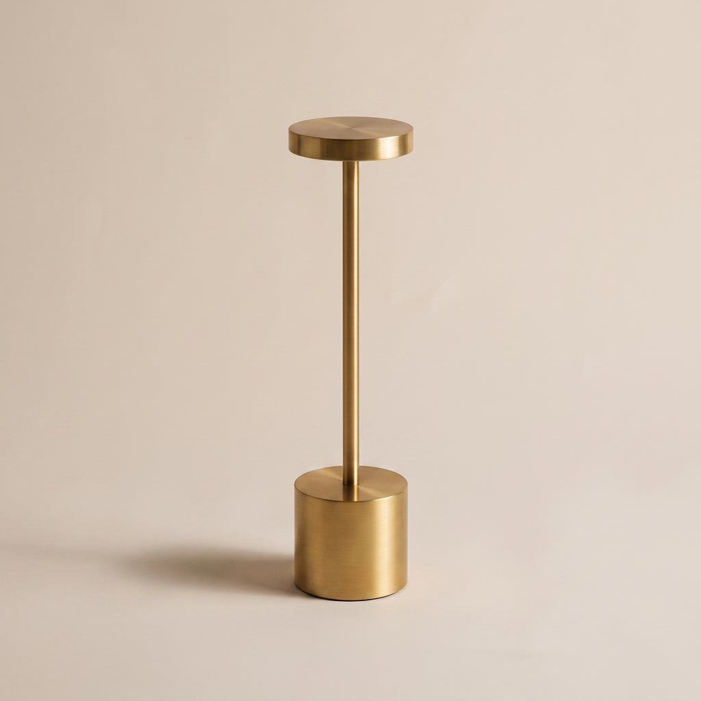 Lampe de table tactile dorée posée, éteinte, sur un fond clair