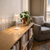 Lampe de chevet effet cristal allumée sur une bibliothèque basse en bois clair, entre une plante verte et une tasse, dans un salon clair