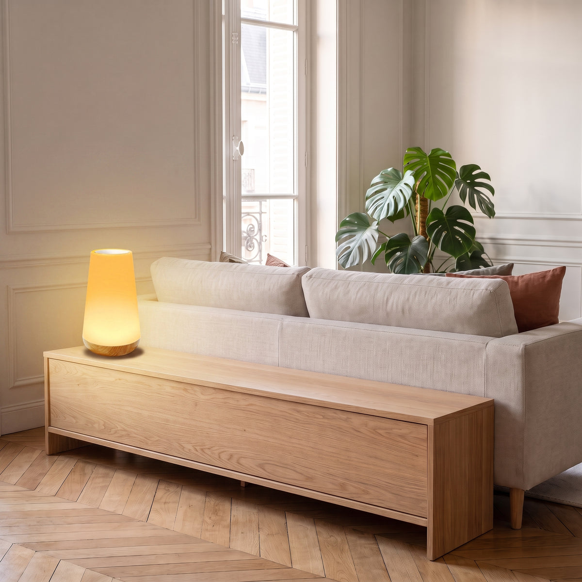 Lampe de chevet tactile allumée sur une console en bois dans un salon aux tons naturels