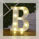 Lettre lumineuse LED B blanche allumée et posée sur un meuble