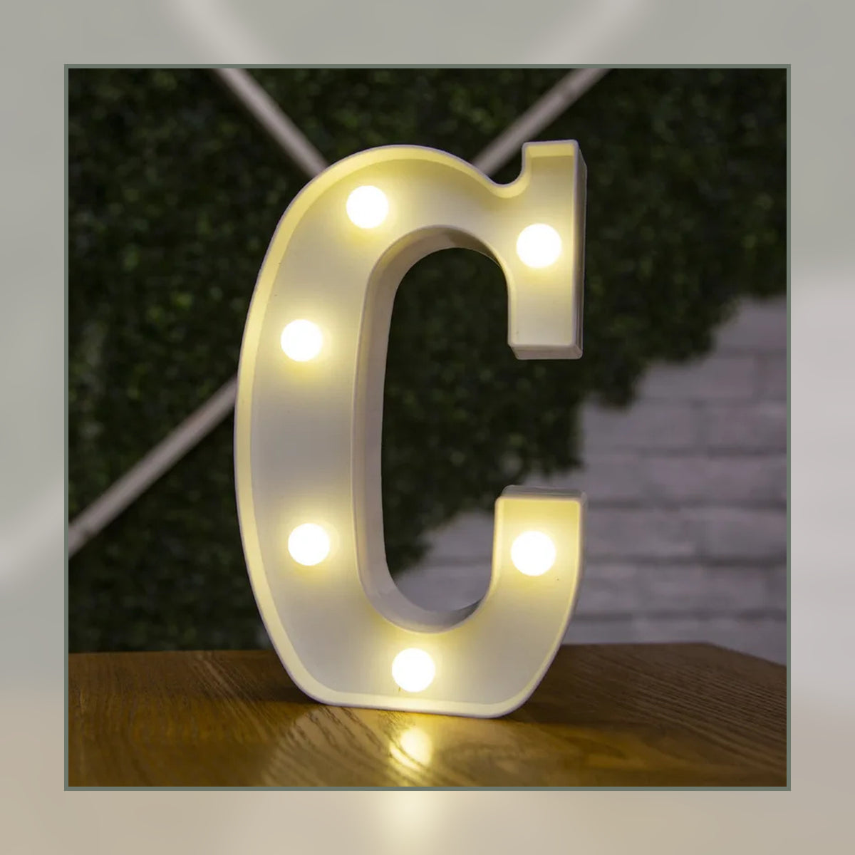 Lettre lumineuse LED C blanche allumée et posée sur un meuble