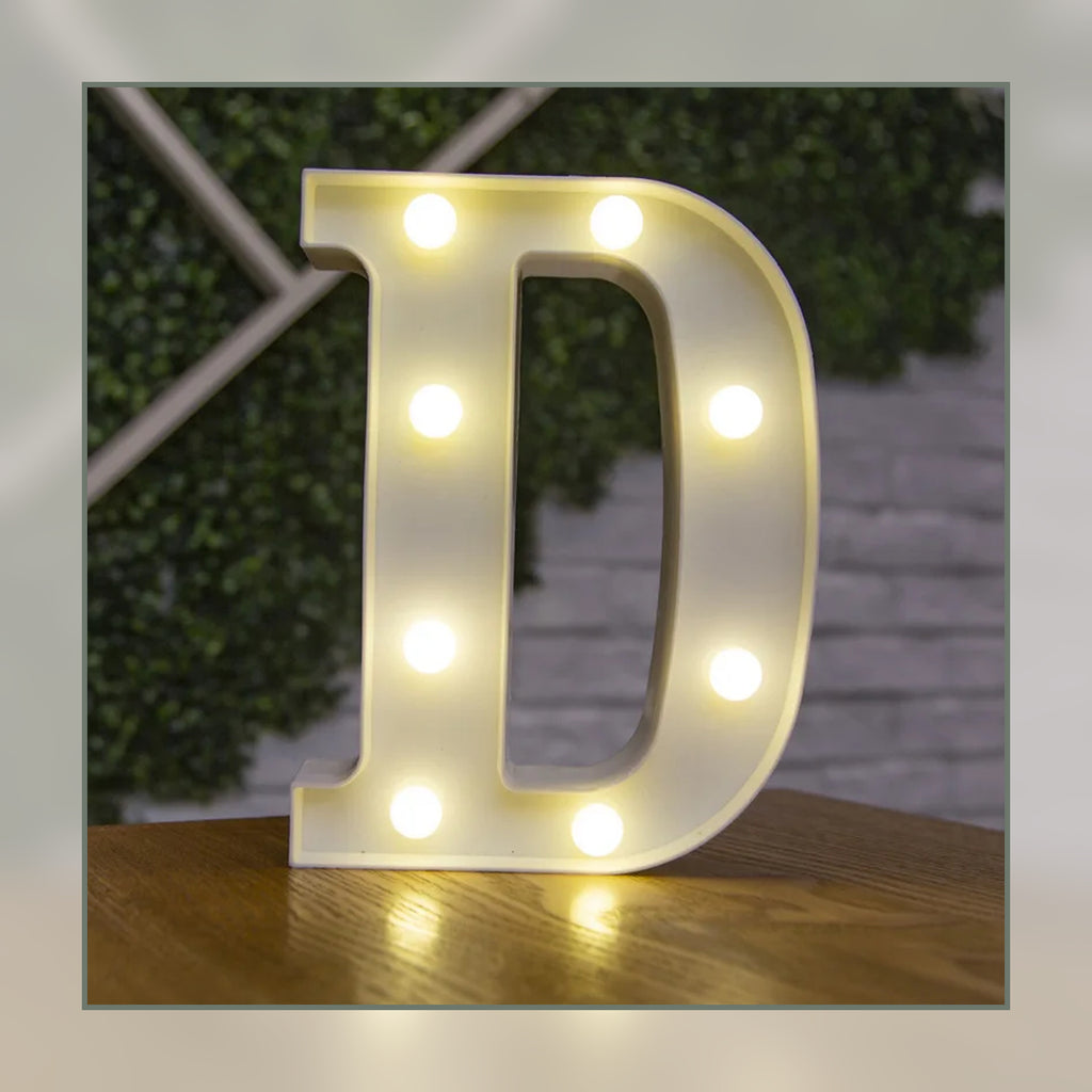 Lettre lumineuse LED D blanche allumée et posée sur un meuble