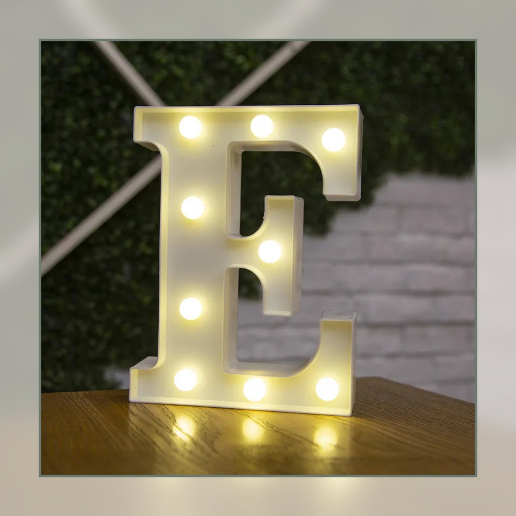 Lettre lumineuse LED E blanche allumée et posée sur un meuble