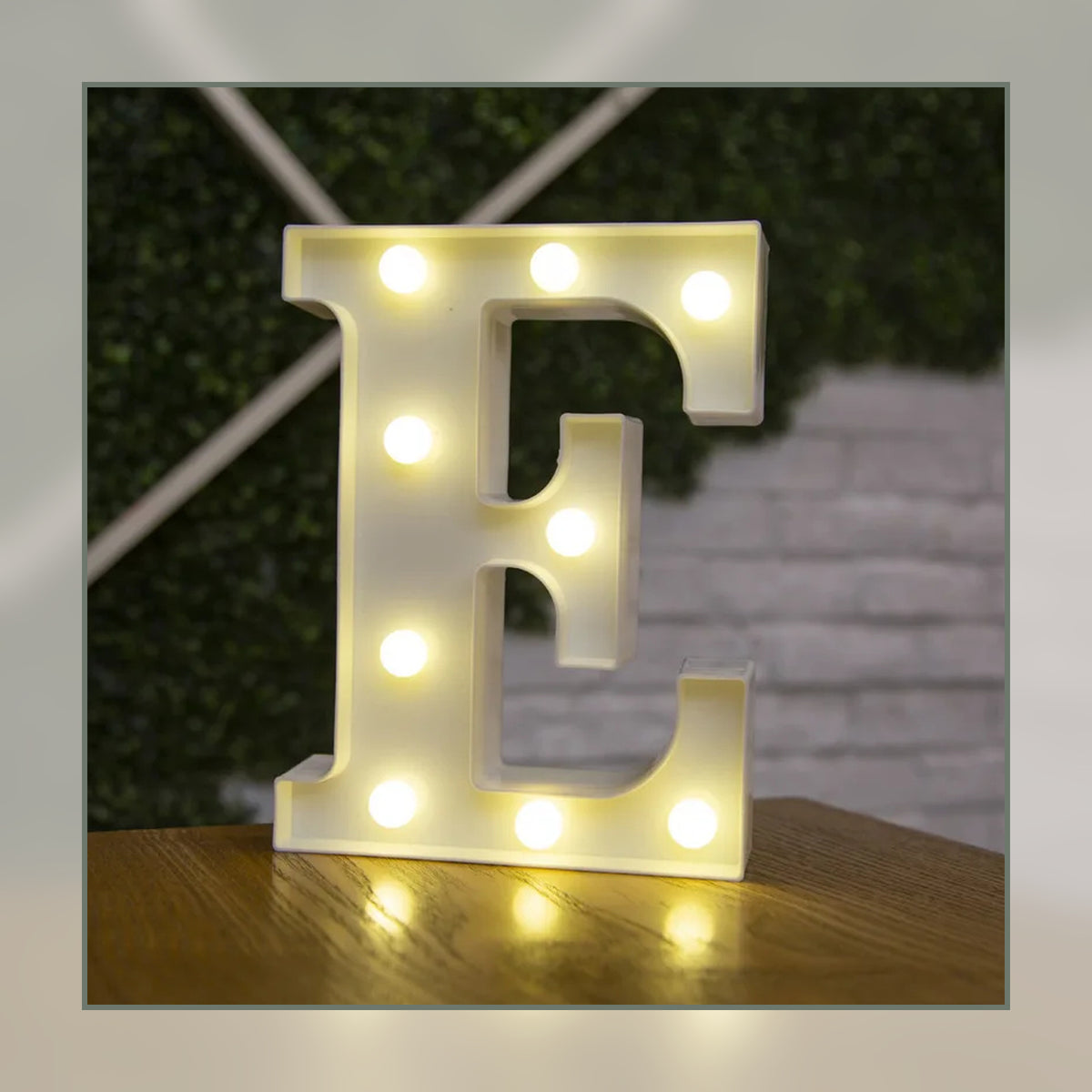 Lettre lumineuse LED E blanche allumée et posée sur un meuble