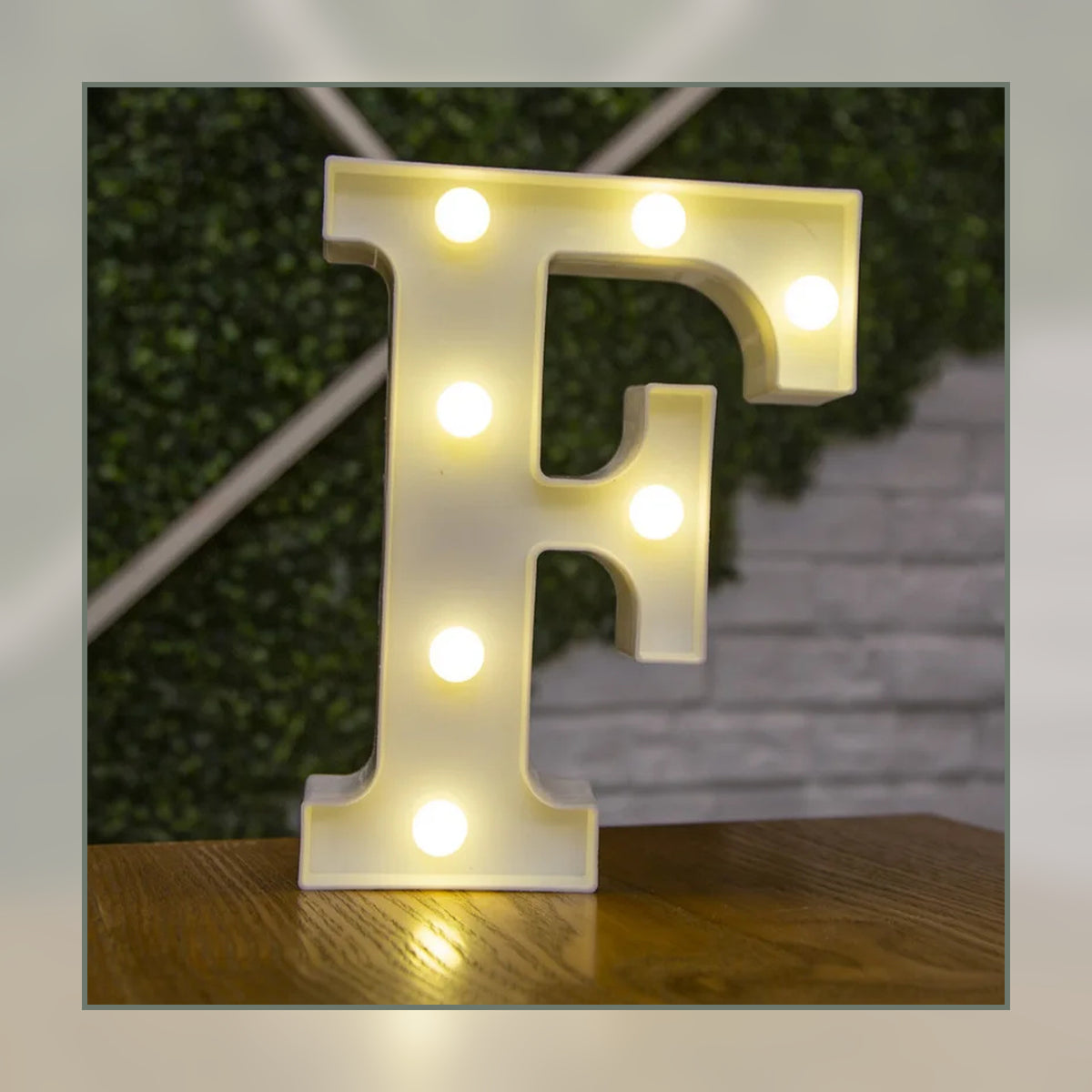 Lettre lumineuse LED F blanche allumée et posée sur un meuble