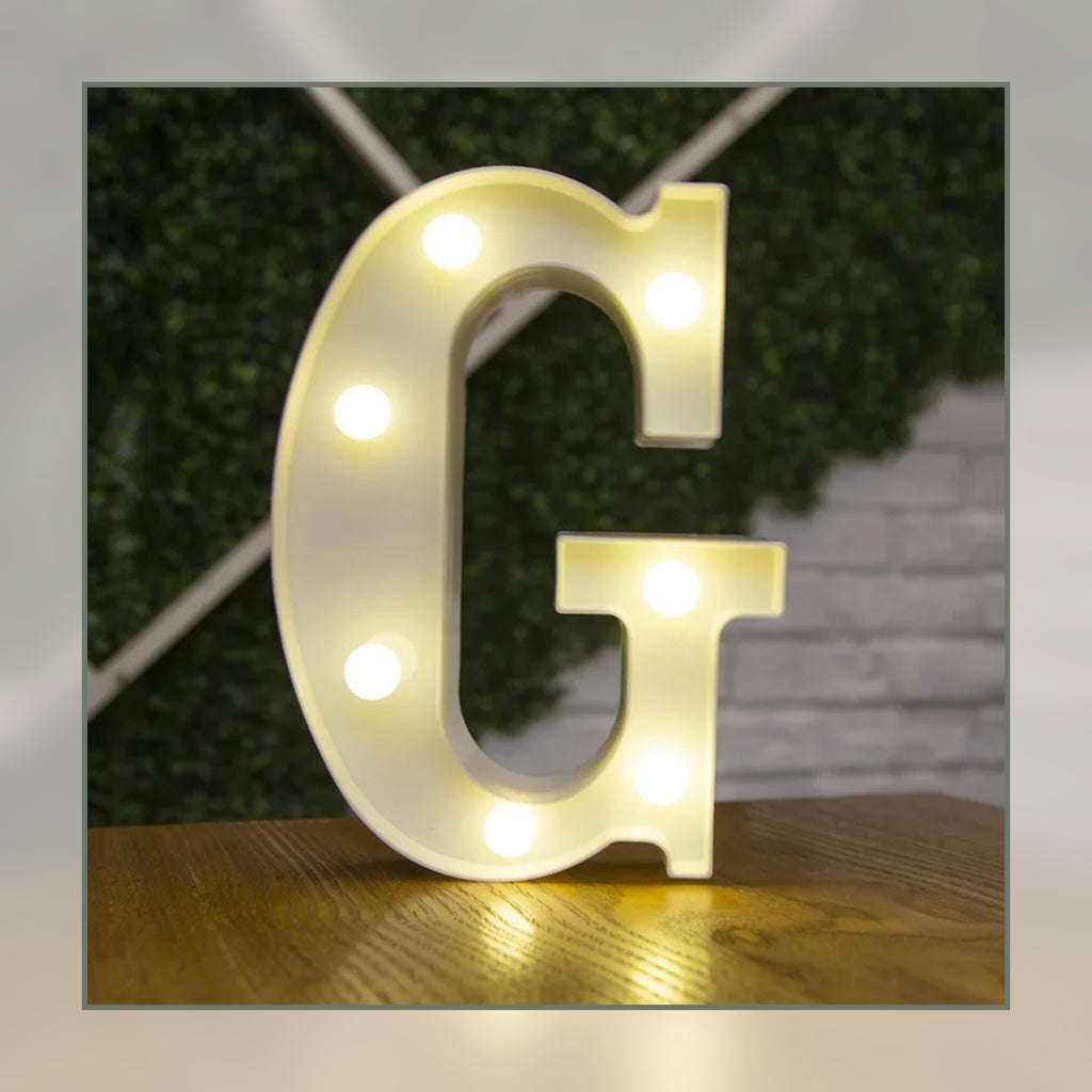 Lettre lumineuse LED G blanche allumée et posée sur un meuble