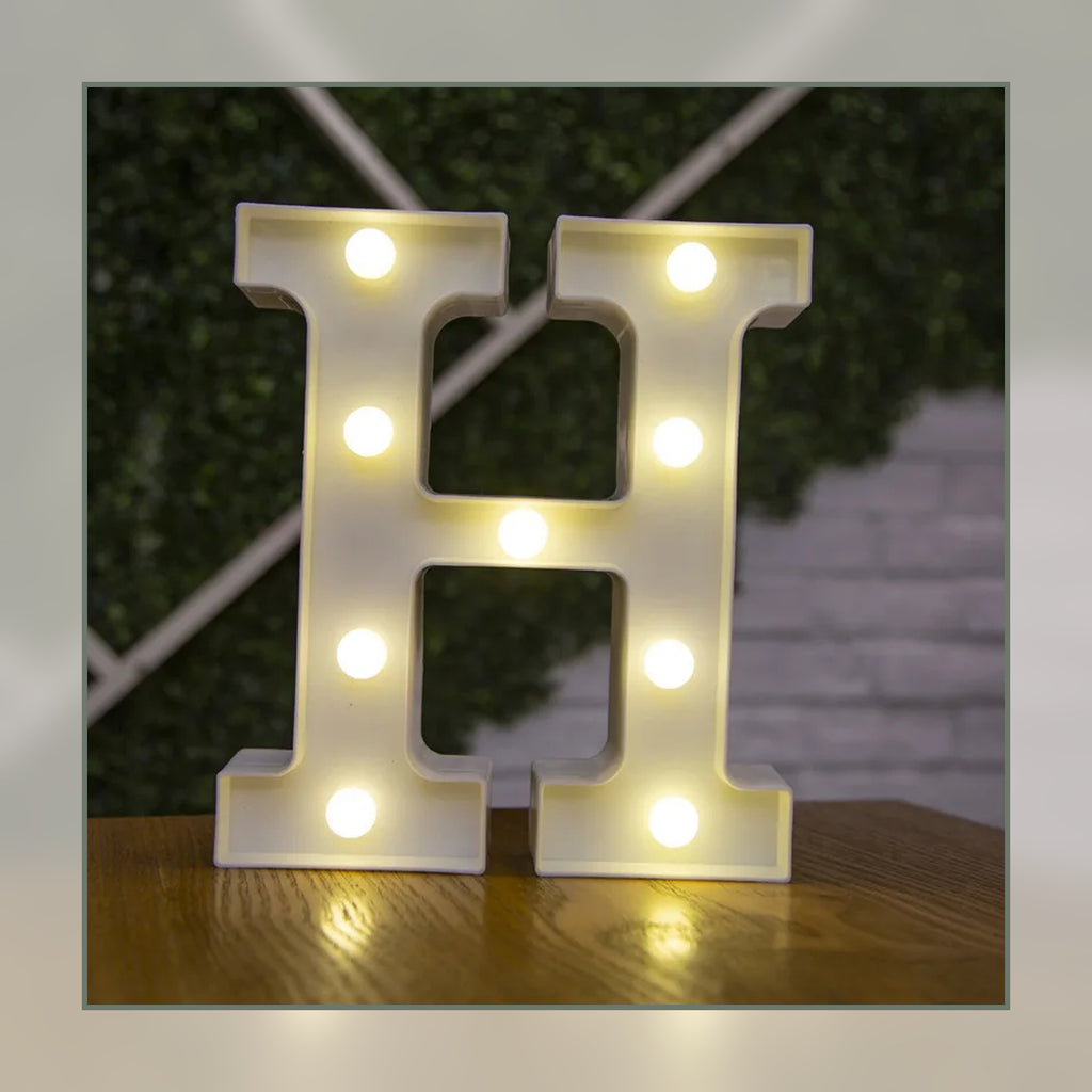 Lettre lumineuse LED H blanche allumée et posée sur un meuble