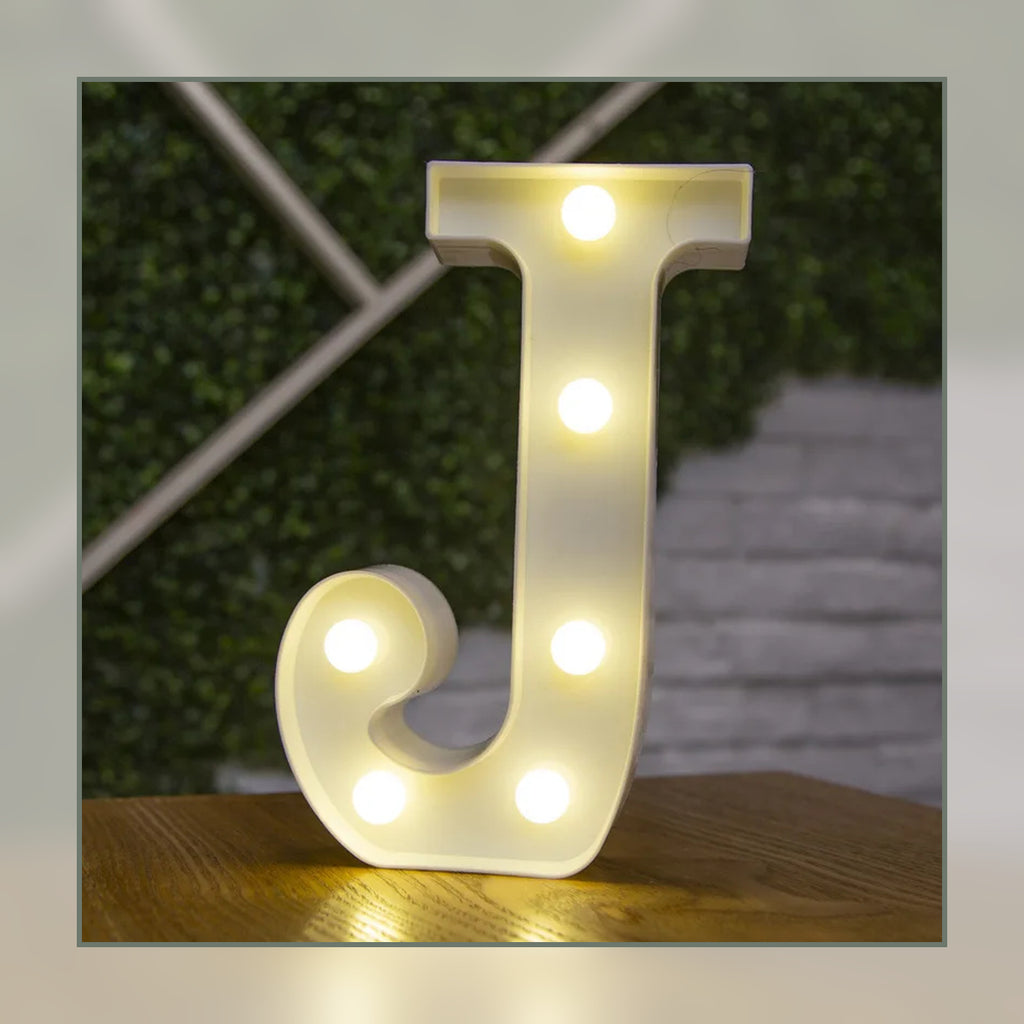 Lettre lumineuse LED J blanche allumée et posée sur un meuble