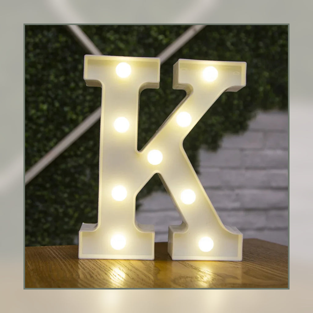 Lettre lumineuse LED K blanche allumée et posée sur un meuble