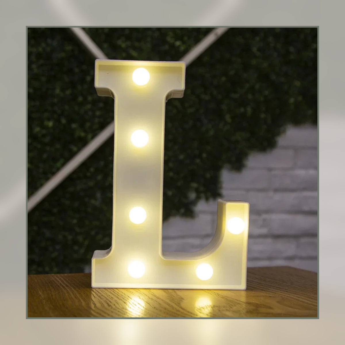 Lettre lumineuse LED L blanche allumée et posée sur un meuble