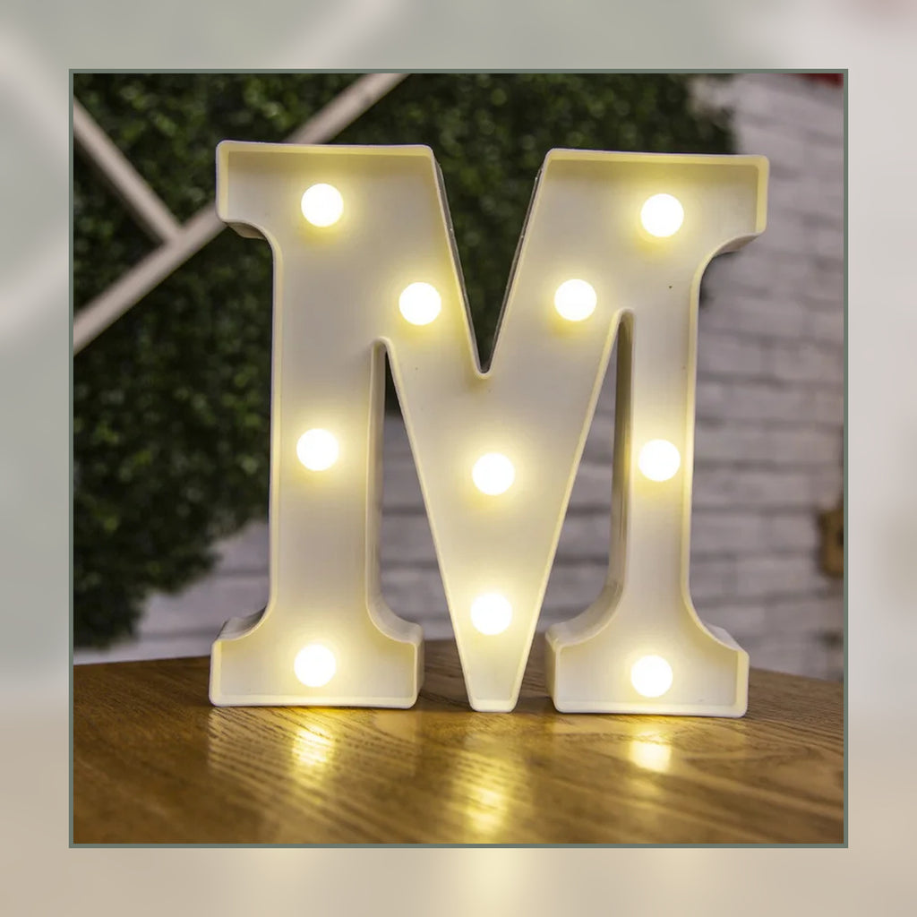 Lettre lumineuse LED M blanche allumée et posée sur un meuble