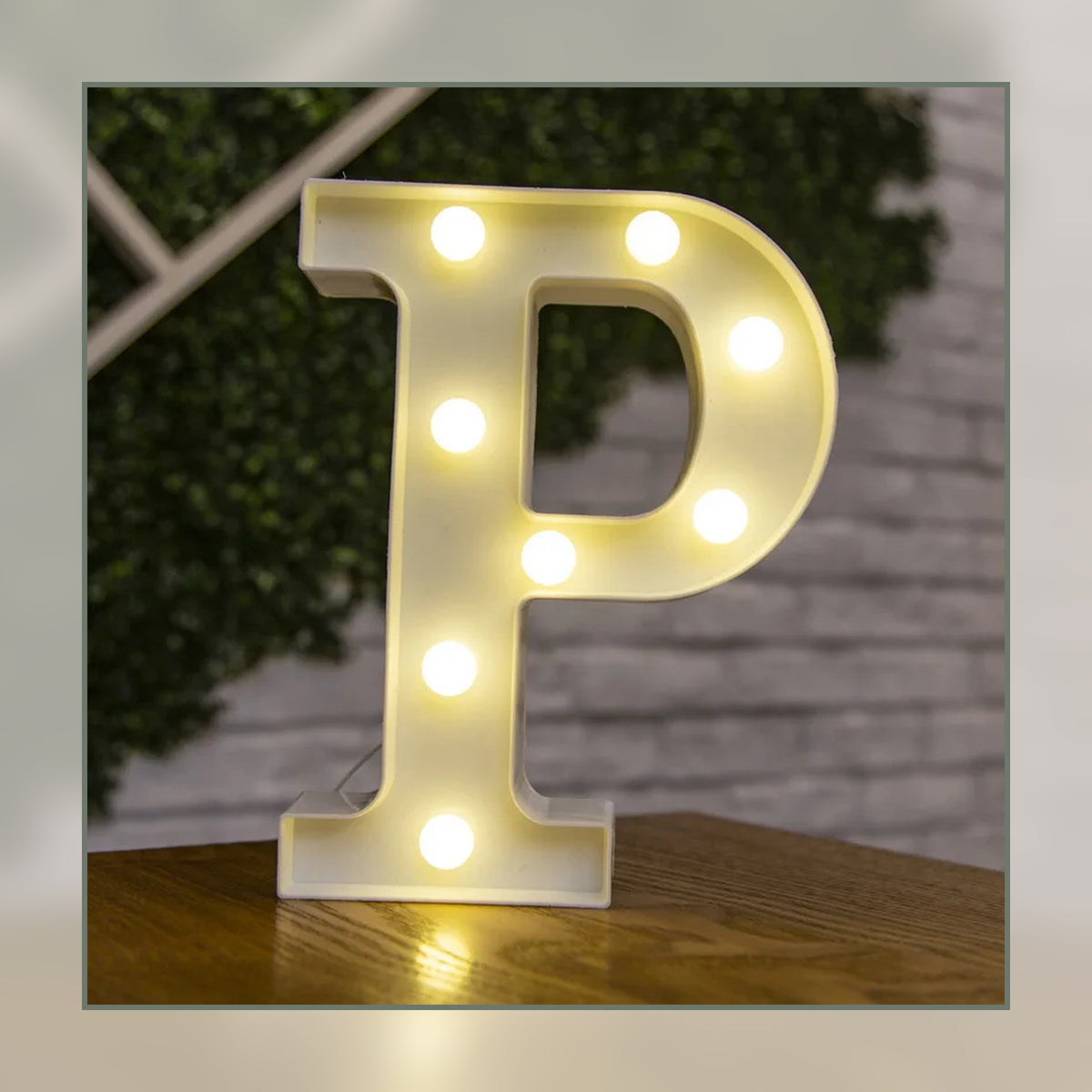 Lettre lumineuse LED P blanche allumée et posée sur un meuble