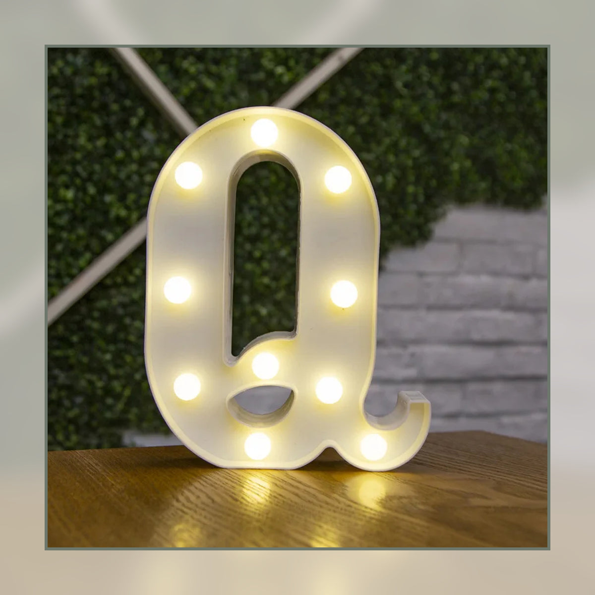 Lettre lumineuse LED Q blanche allumée et posée sur un meuble