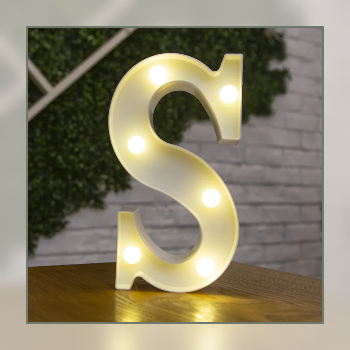 Lettre lumineuse LED S blanche allumée et posée sur un meuble