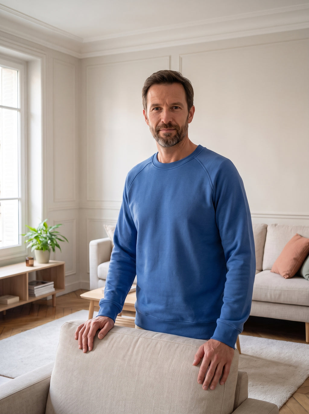 Homme portant le sweat classique bleu près d'un fauteuil clair