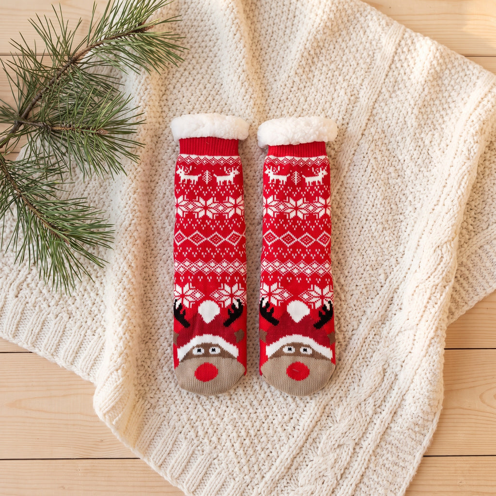 Chaussettes de Noël rouges à jacquard et renne posées à plat sur un plaid
