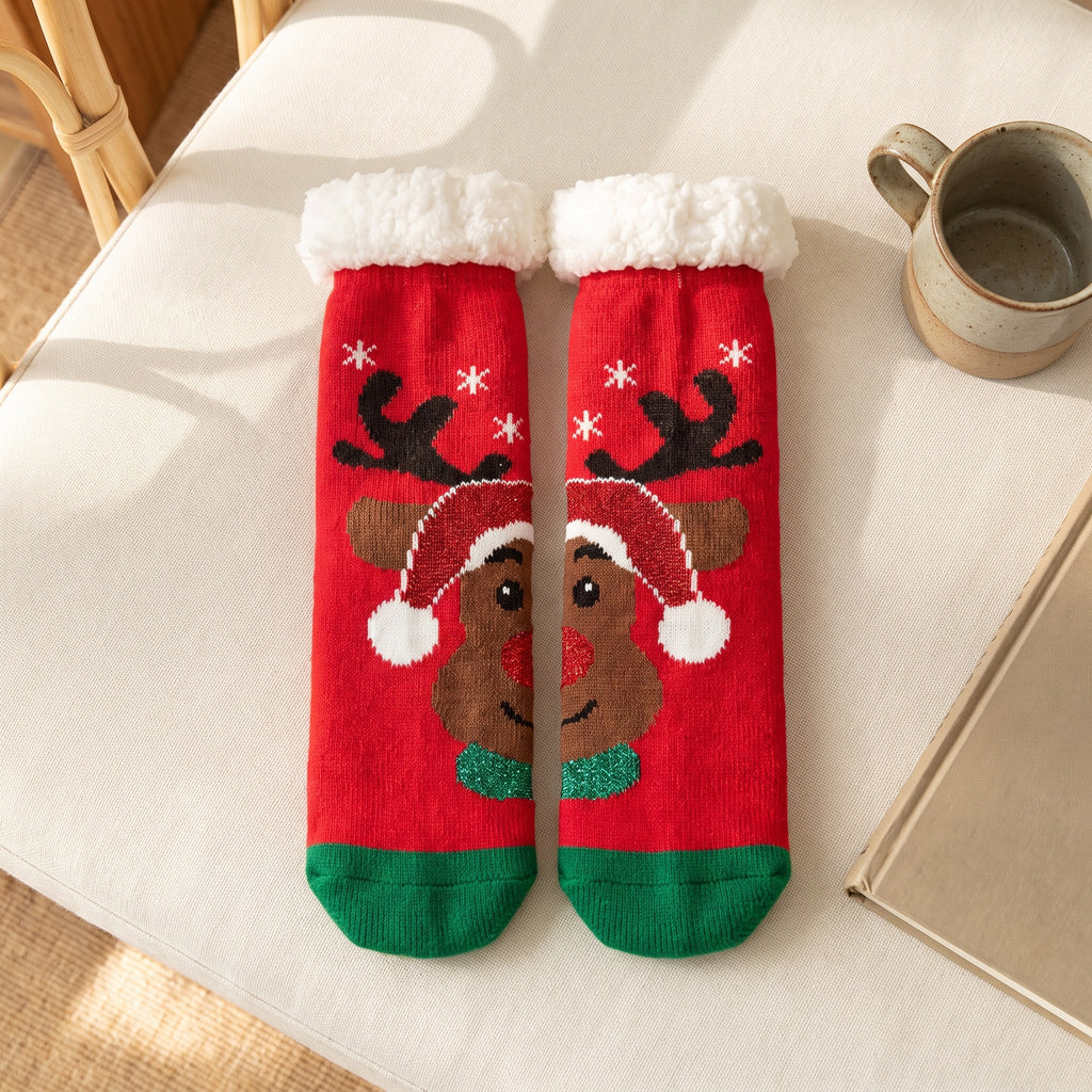 Chaussettes de Noël rouges à renne au bonnet posées à plat sur le canapé