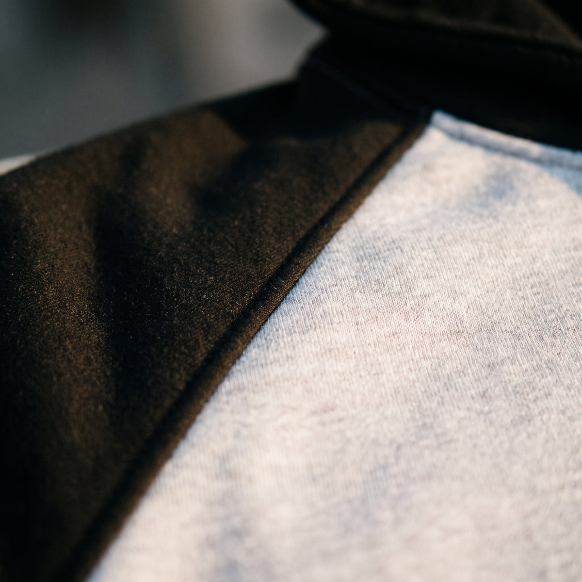 Détail de la couture raglan entre la manche noire et le corps gris