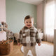 Enfant debout portant le manteau bébé à carreaux marron et écru