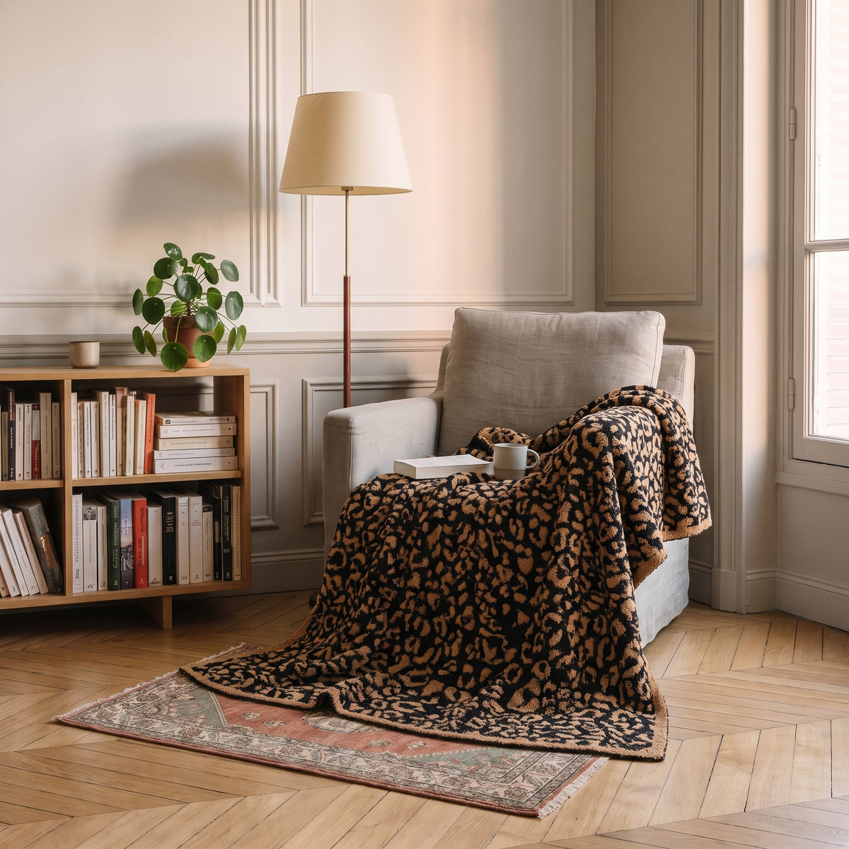Plaid léopard camel et noir posé sur un fauteuil de lecture