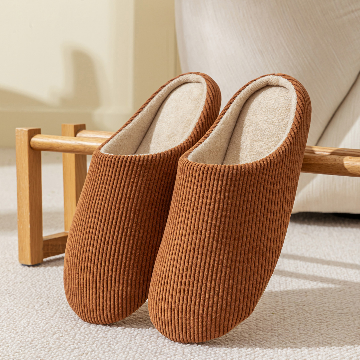 Paire de chaussons homme marron en velours côtelé posée dans un salon chaleureux