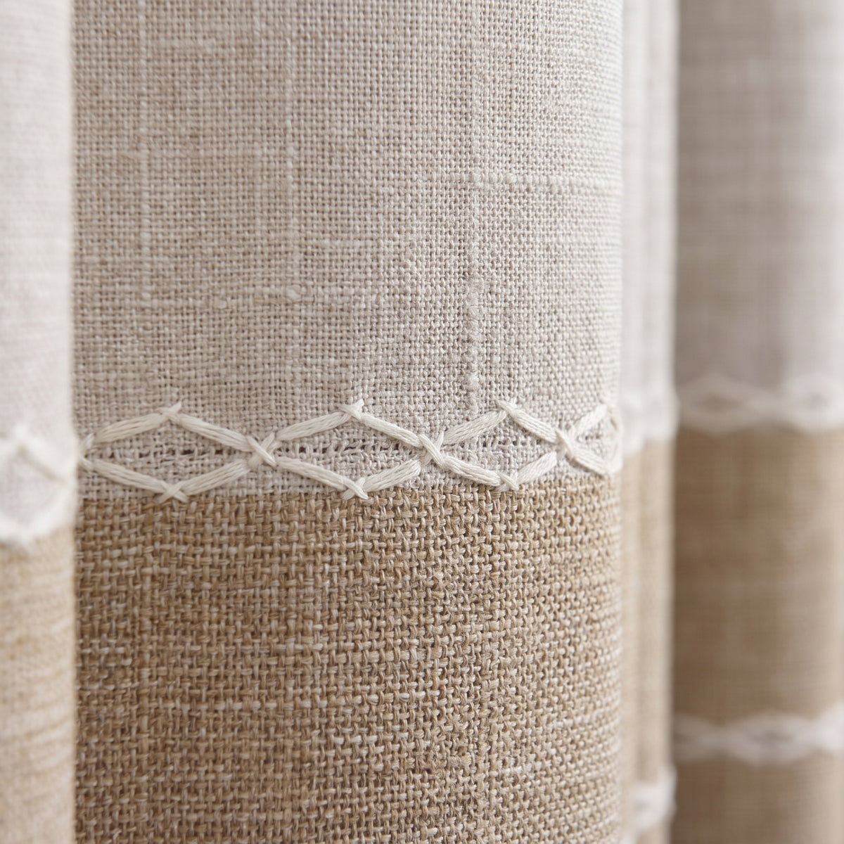 Macro du coton tissé beige : trame aérée en haut, trame serrée en bas, galon brodé ivoire au milieu Image
