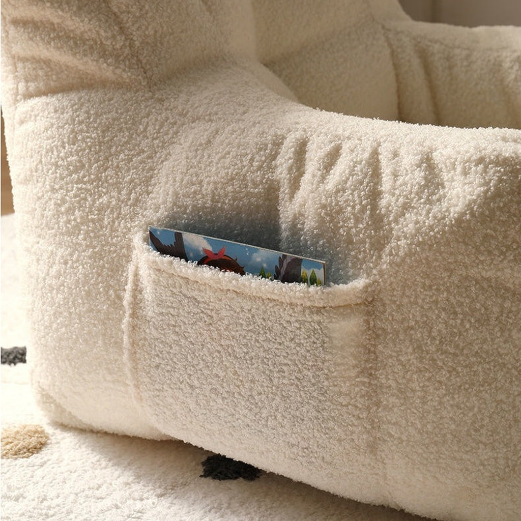 Poche latérale et surface bouclée du fauteuil enfant beige avec un album rangé