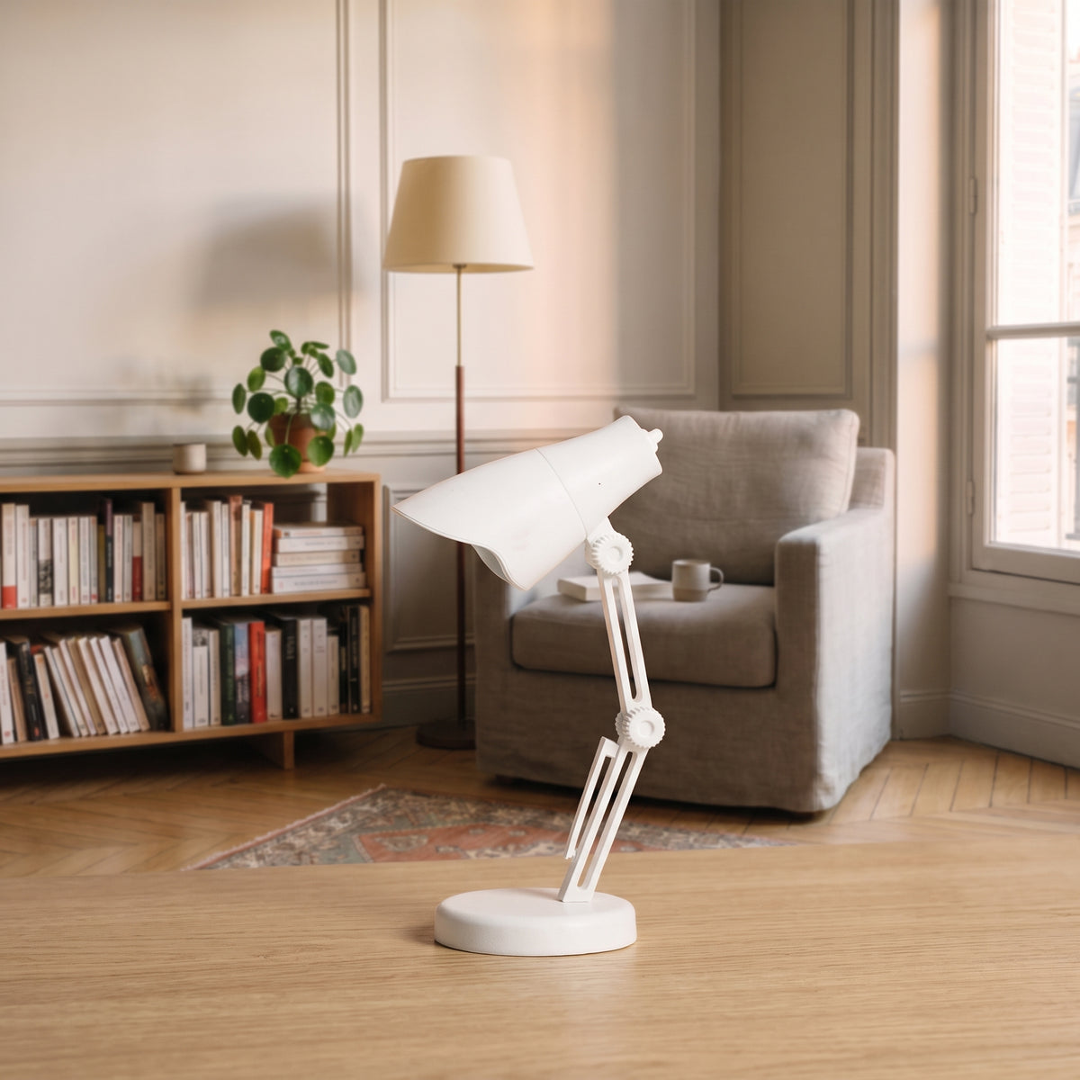 Mini lampe de lecture blanche à abat-jour facetté posée sur un plan de travail en bois clair, vue de trois quarts