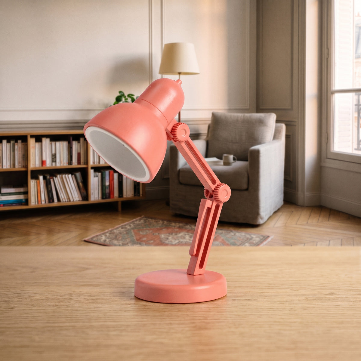 Mini lampe de lecture corail à abat-jour rond posée sur un plan de travail en bois clair, vue de trois quarts