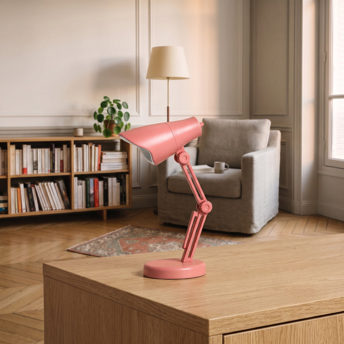 Mini lampe de lecture rose corail à abat-jour facetté posée sur un plan de travail en bois clair, vue de trois quarts