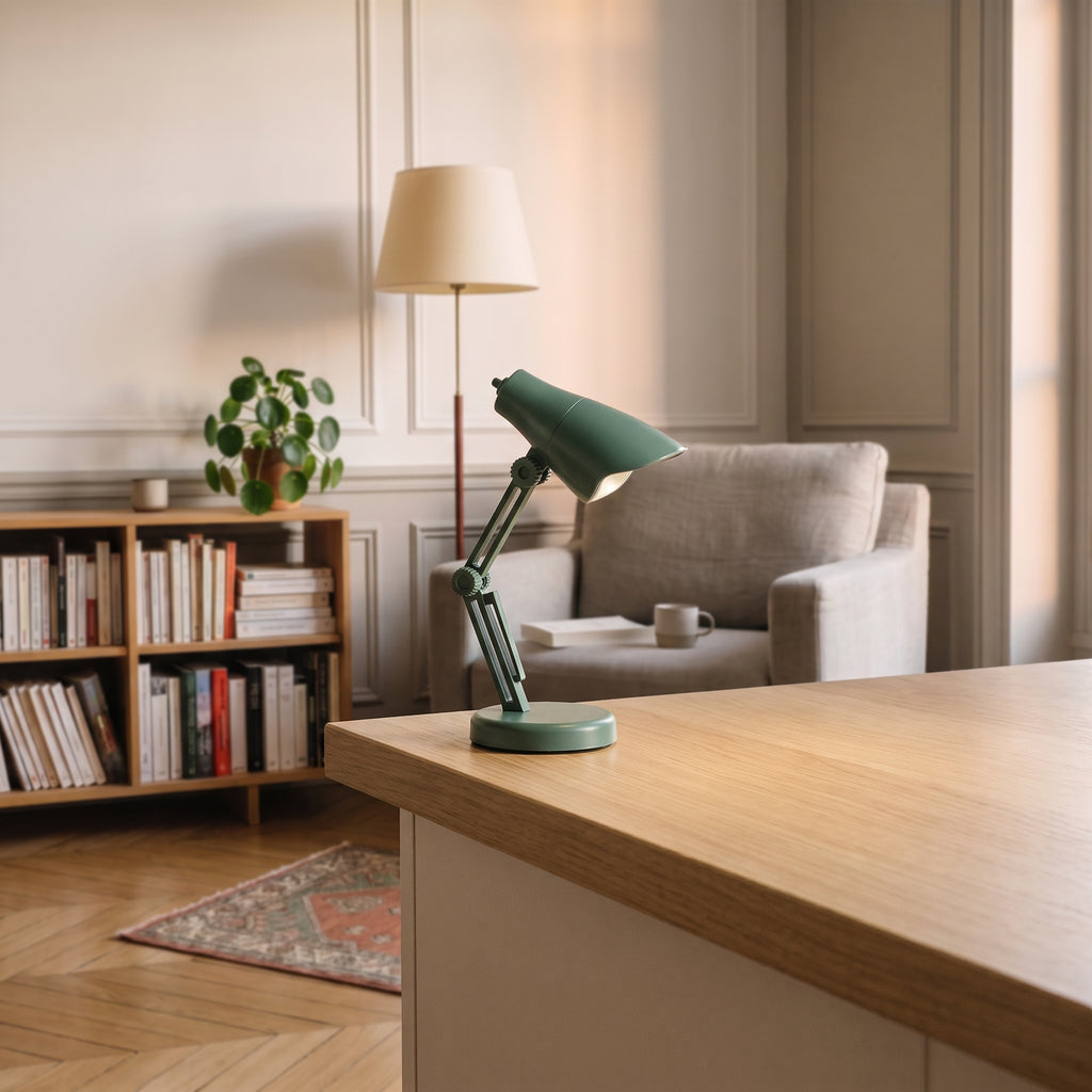 Mini lampe de lecture vert sauge à abat-jour facetté posée sur un plan de travail en bois clair, vue de trois quarts
