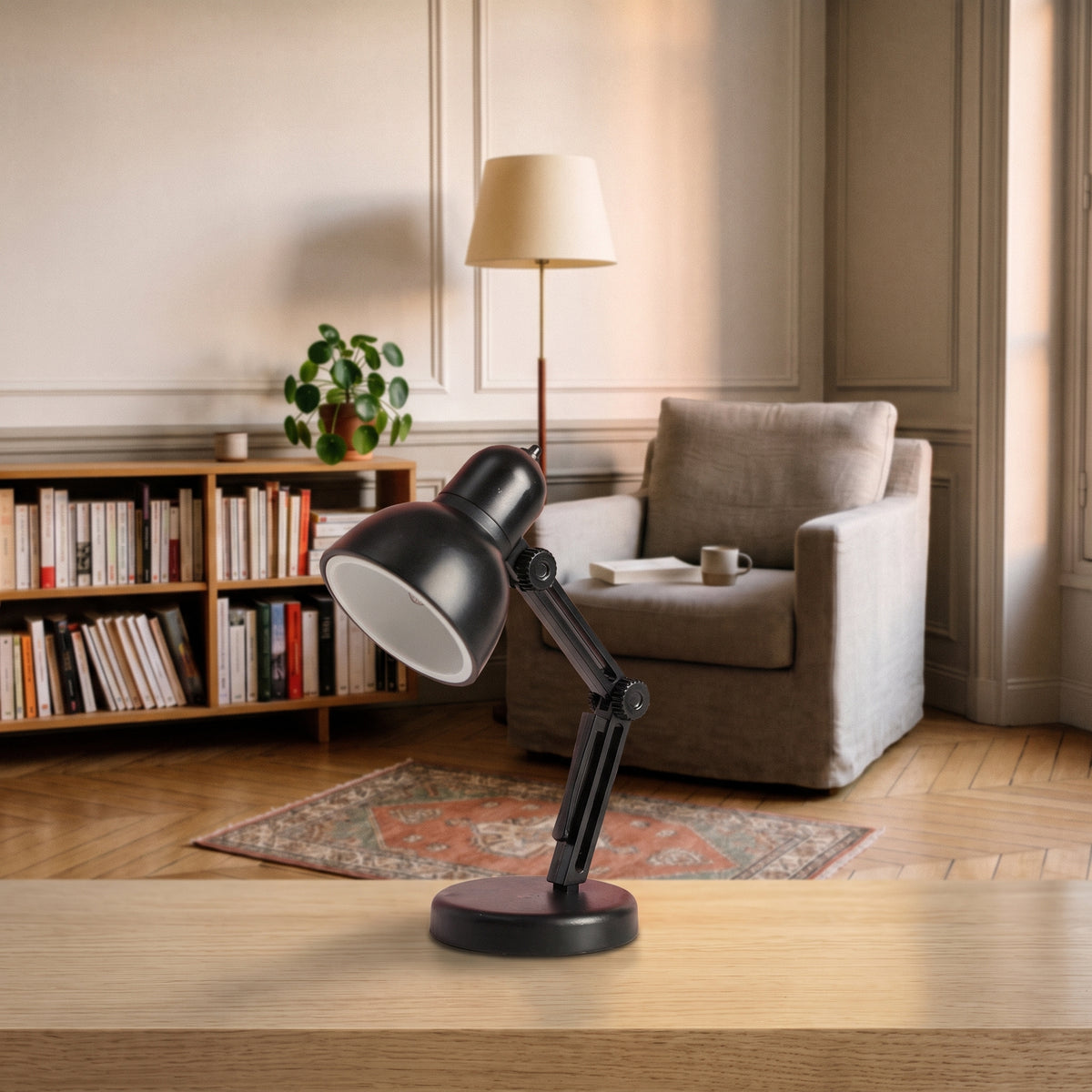 Mini lampe de lecture noire à abat-jour rond posée sur un plan de travail en bois clair, vue de trois quarts