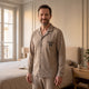 Homme portant le pyjama taupe avec écusson dans une chambre lumineuse