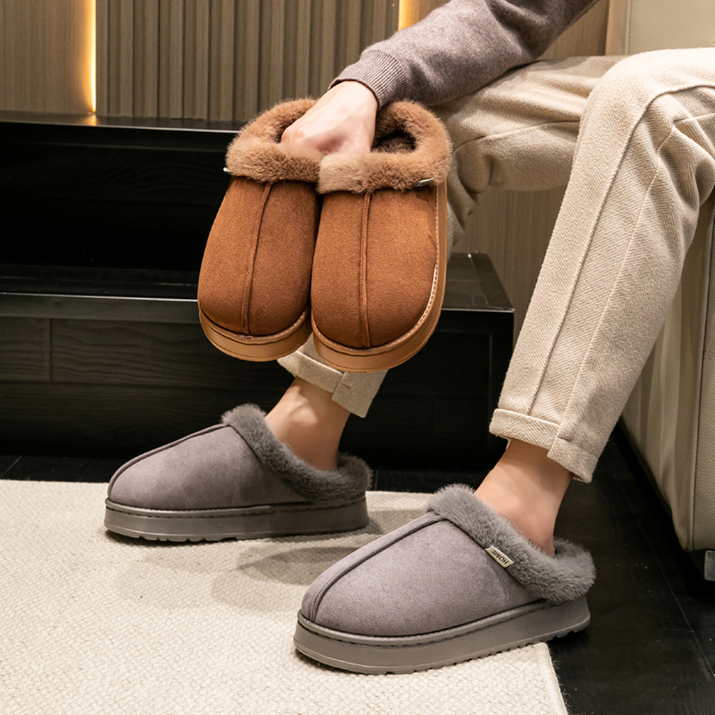 Mules fourrées homme portées aux pieds, vues en Gris avec la paire Café en main