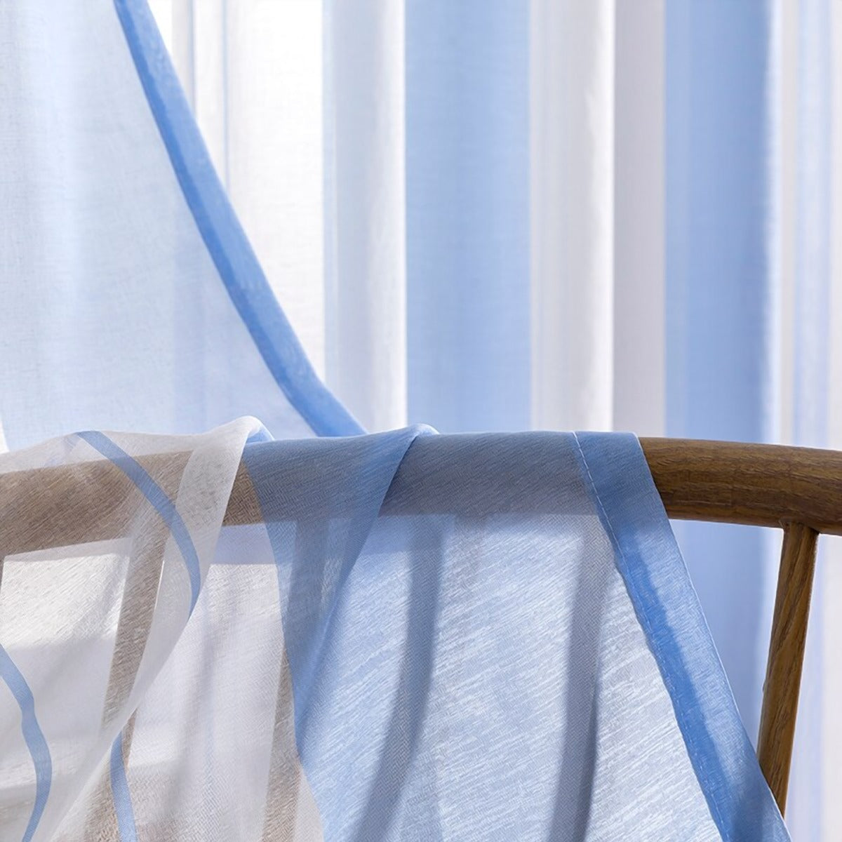 Voilage rayé bleu clair et blanc posé sur un dossier de chaise, trame vue de près