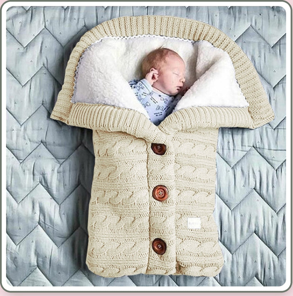 Bébé installé dans le nid d’ange beige tricoté à trois boutons