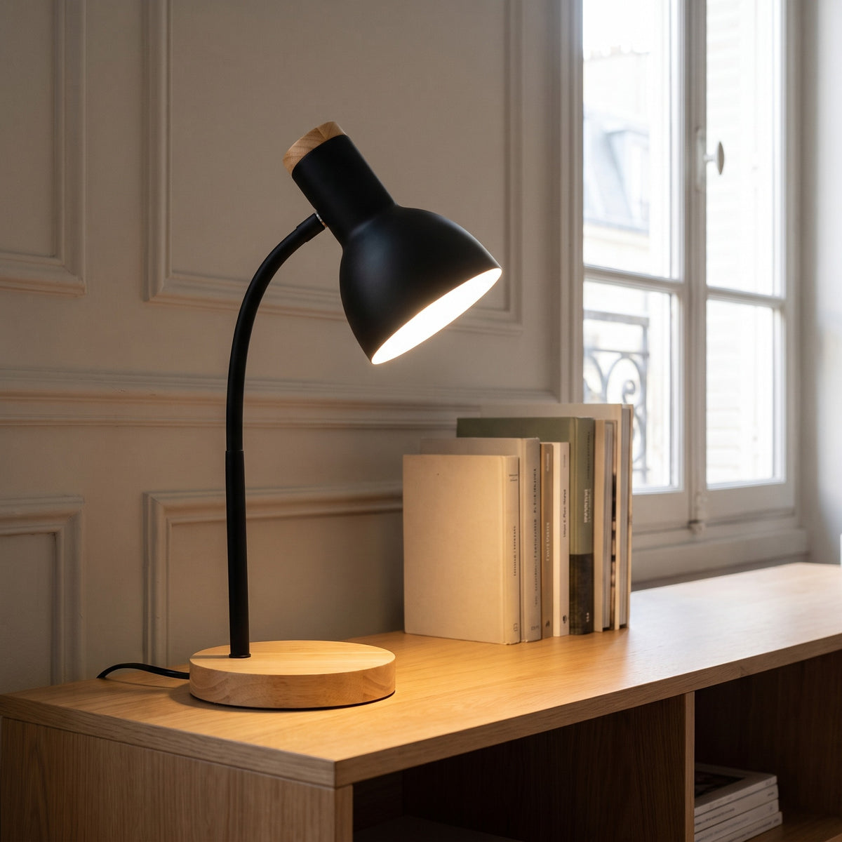 Lampe de bureau noire allumée sur un bureau en bois sous la fenêtre