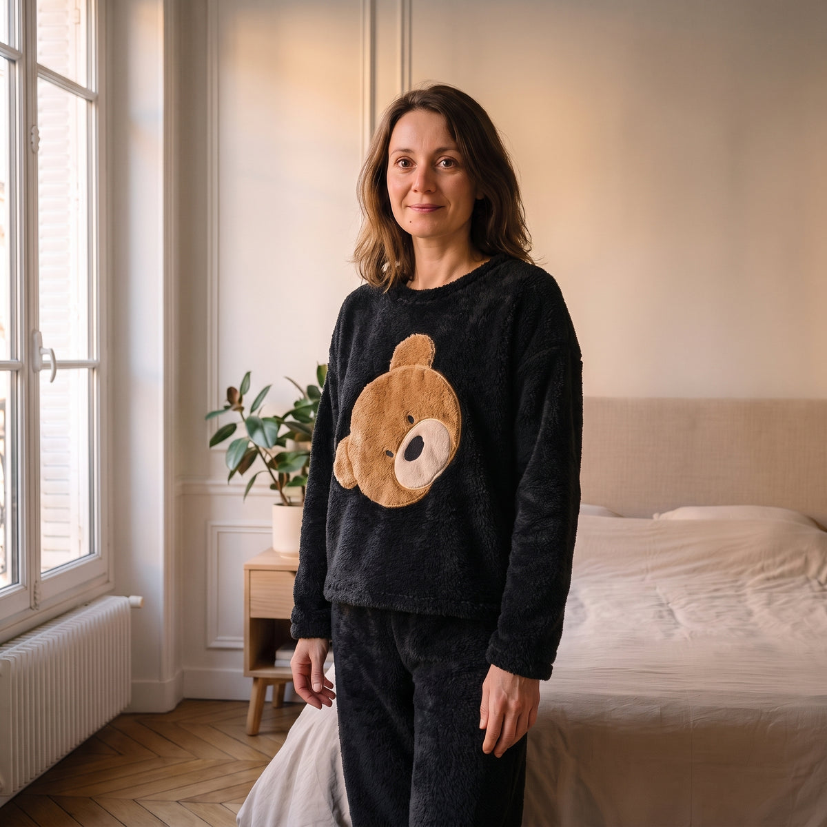 Femme portant le pyjama d'hiver noir grand ours dans une chambre lumineuse