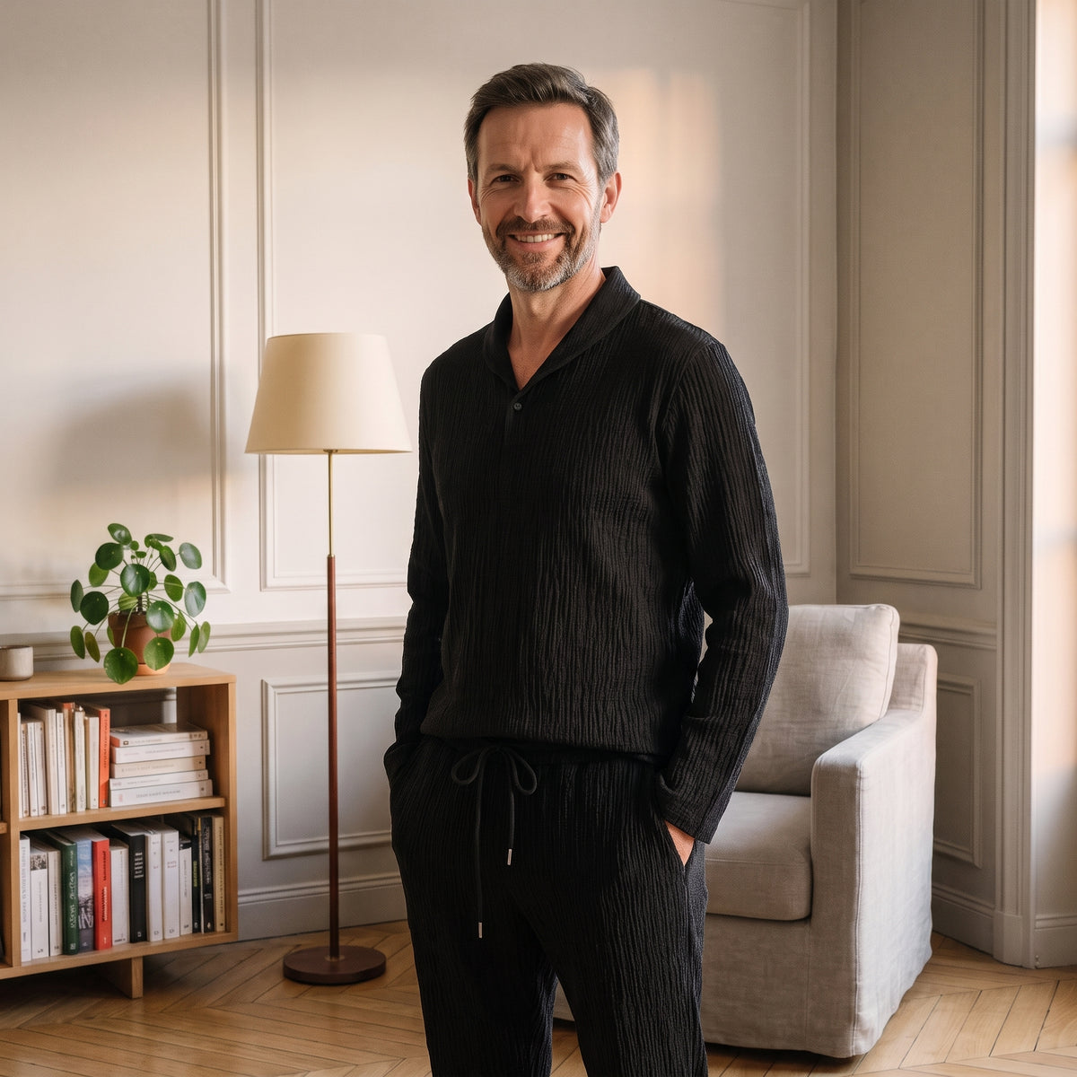 Homme dans un coin lecture avec l’ensemble noir et les mains dans les poches du pantalon