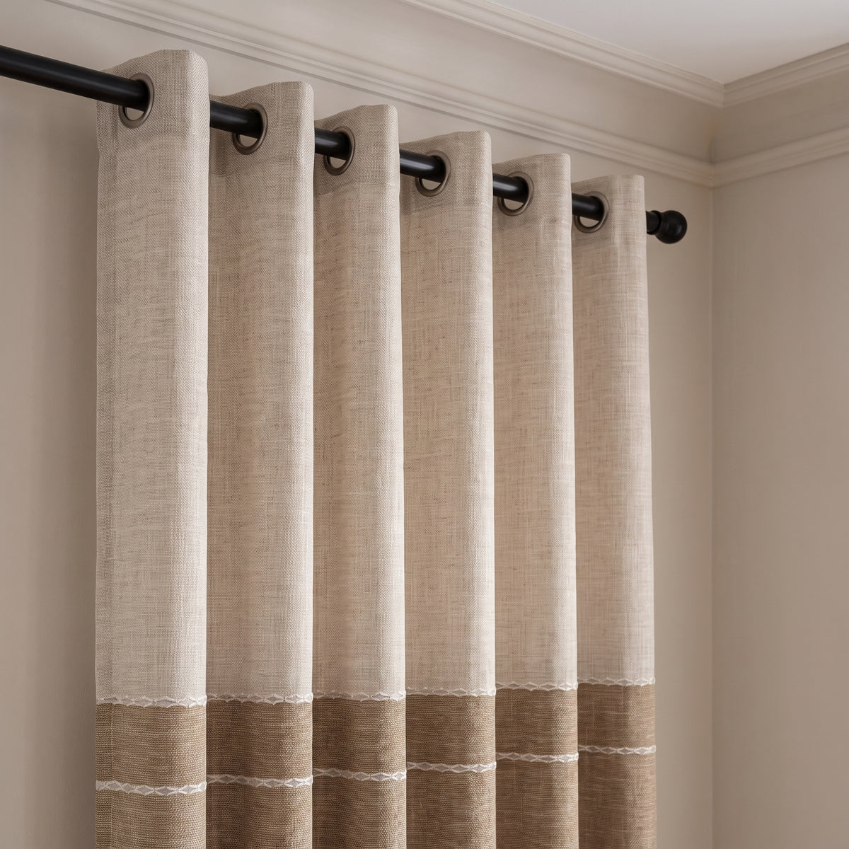 Gros plan sur les œillets métalliques du rideau d'ombrage beige enfilés sur une tringle noire