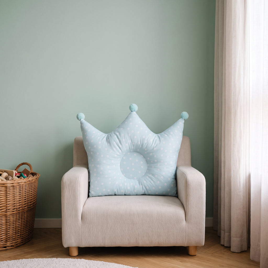 Oreiller couronne bleu clair pour bébé sur un fauteuil d’enfant