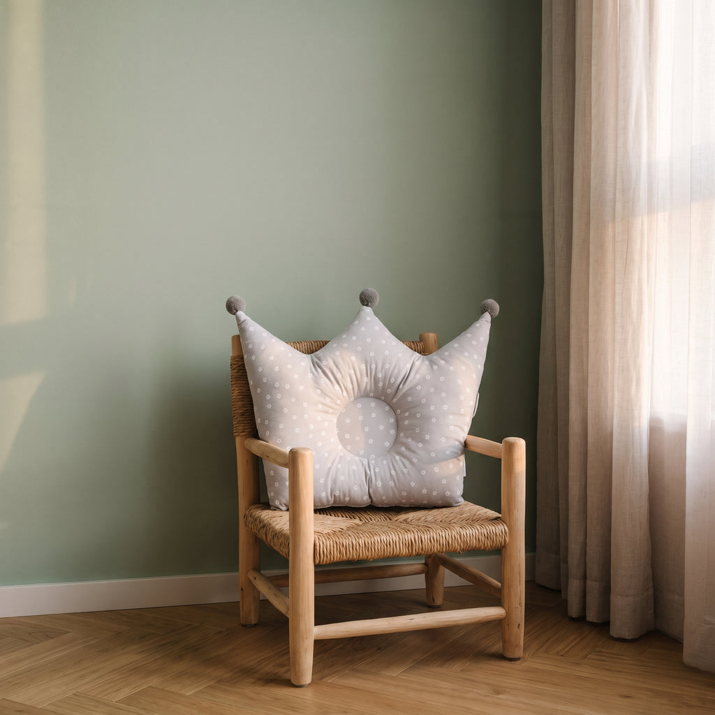 Oreiller couronne gris pour bébé sur un fauteuil d’enfant