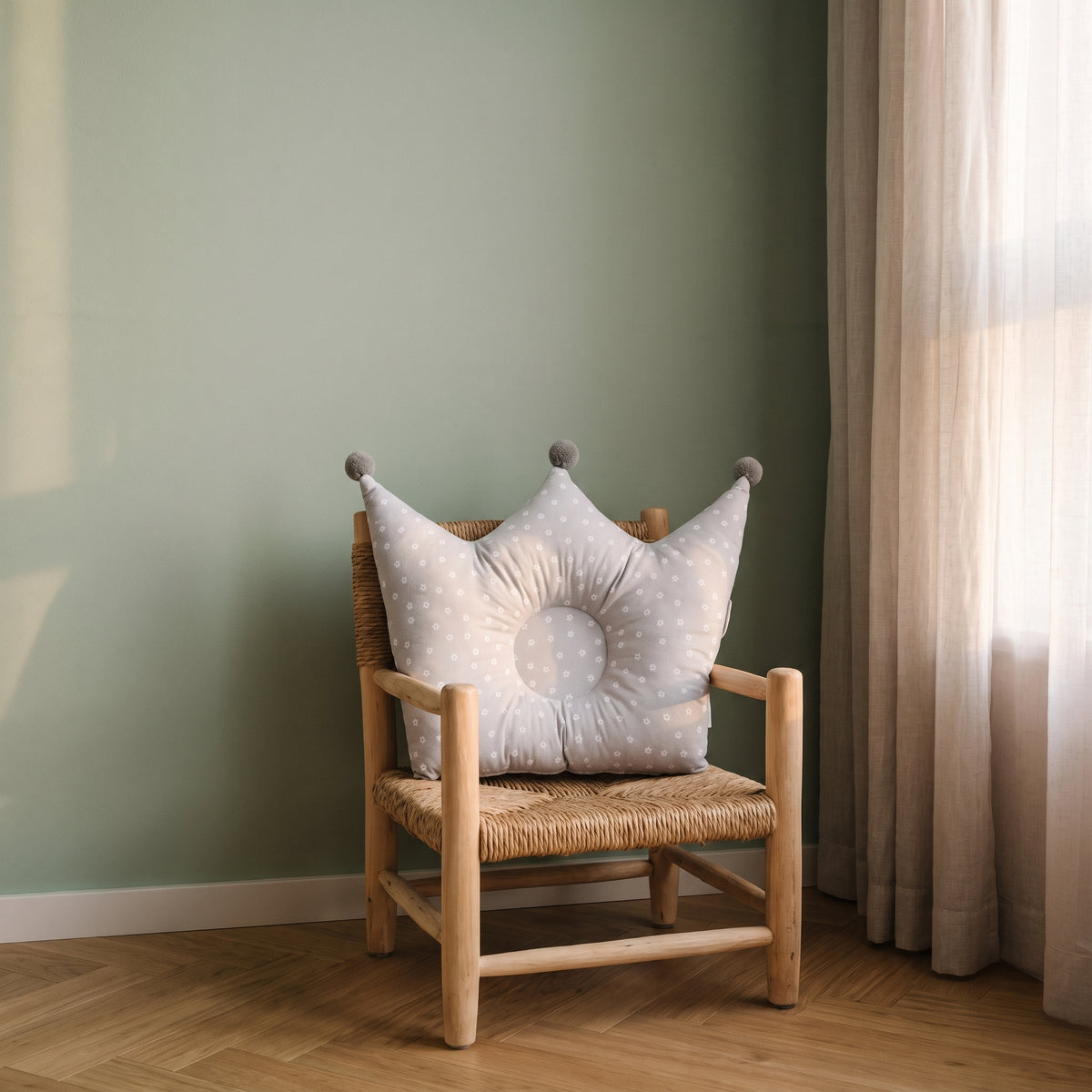 Oreiller couronne gris pour bébé sur un fauteuil d’enfant