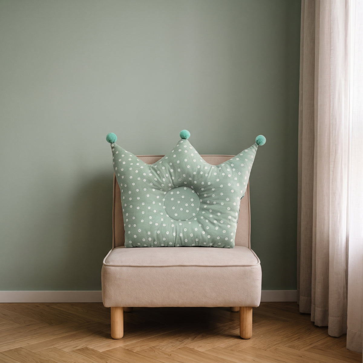 Oreiller couronne vert pour bébé sur un fauteuil d’enfant