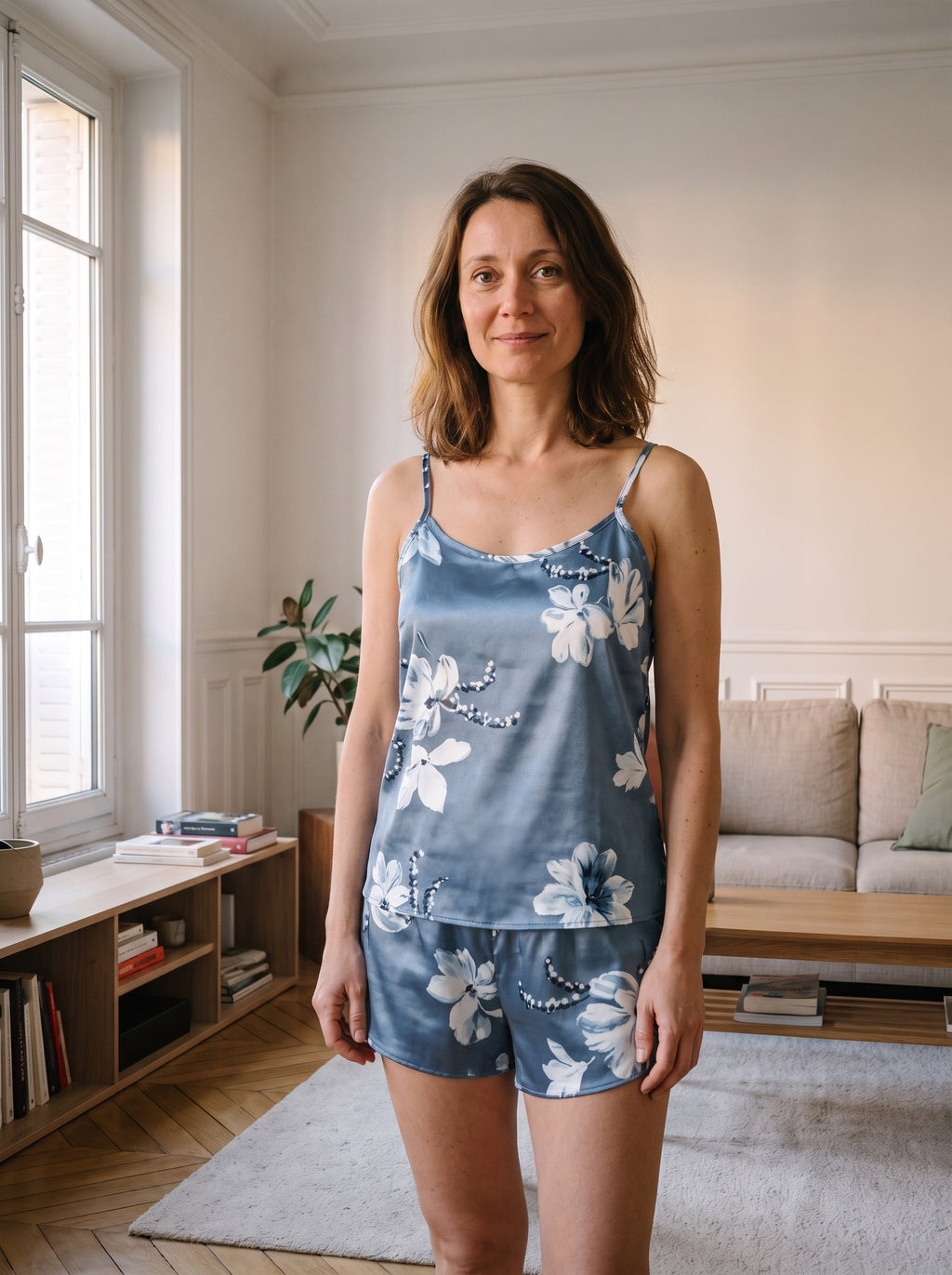 Ensemble pyjama en satin bleu ardoise a fleurs, porte de face dans un salon