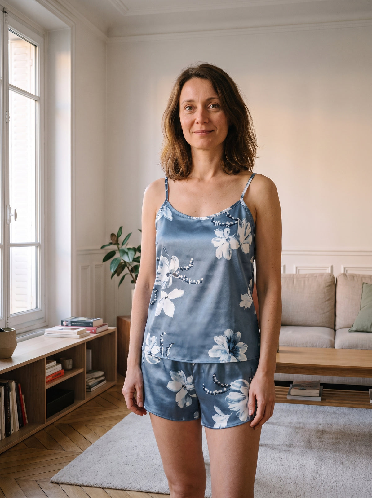 Ensemble pyjama en satin bleu ardoise a fleurs, porte de face dans un salon
