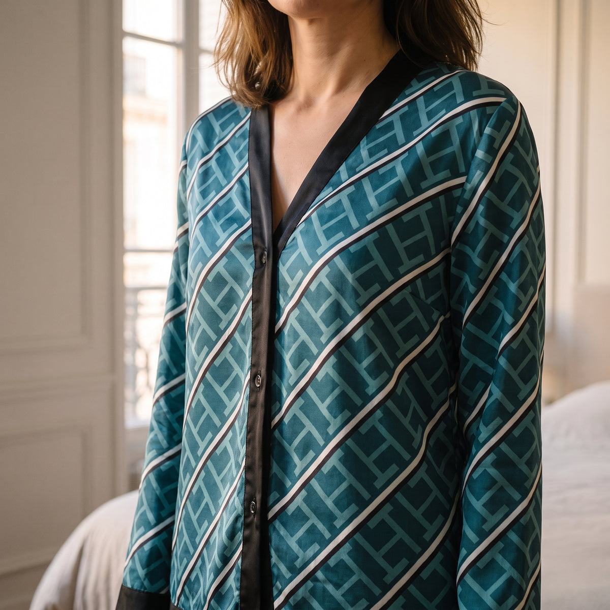 Détail du parement uni qui borde l'encolure et le boutonnage du pyjama en satin bleu canard